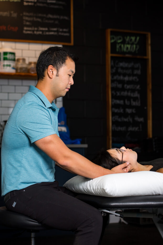 A man is adjusting a woman's neck in a massage room.